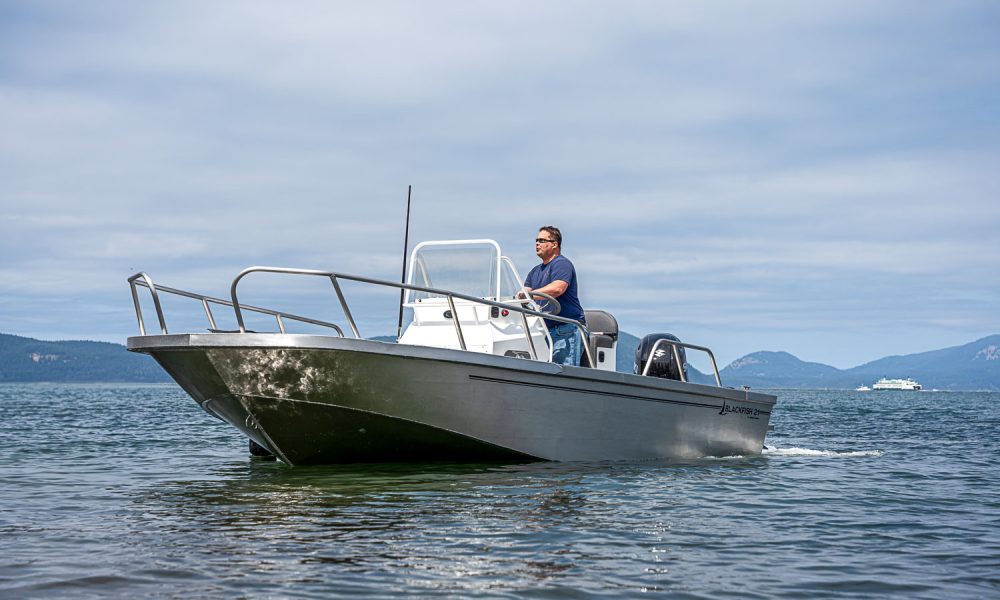Our Blackfish aluminum center console boat sits calmly in the water while owner and CEO of ARMOR Marine stands at the center console